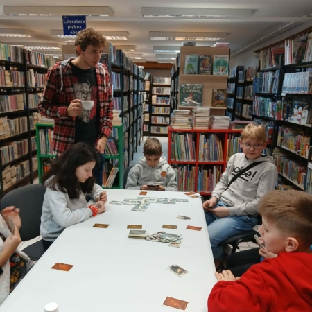 Fotografia kolorowa. Uczestnicy mikołajkowego planszogrania we wnętrzu filii w Górkach Małych.